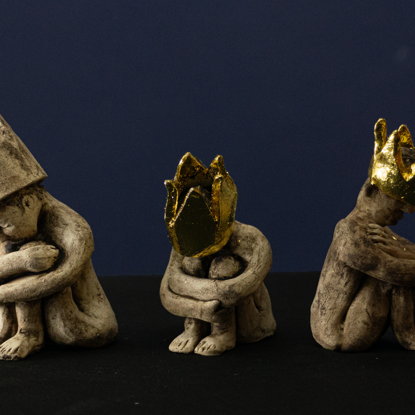 Keramik-Skulpturengruppe „Die Bürde der Erwählten“ von Jutta Eger, Engobe-Oberfläche mit teilweise goldbezogenen Kronen, mehrere figurative Formen als zusammenhängendes Konzept der Bürde, Vorderansicht.