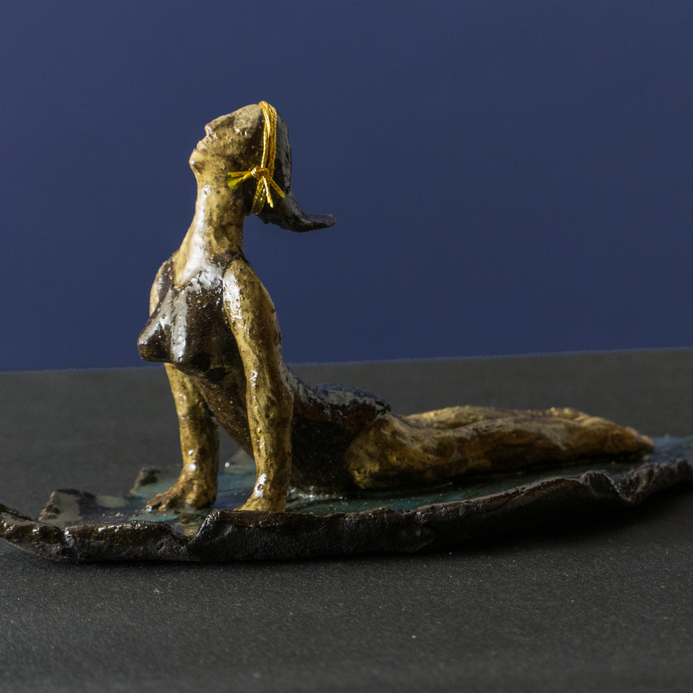 Keramik-Skulptur „Sphinx Yoga“ von Jutta Eger, schwarzer Ton mit glasierter Oberfläche, figurative Form in liegender Haltung mit Bezug zur Yoga-Sphinx-Position, Vorderansicht links.