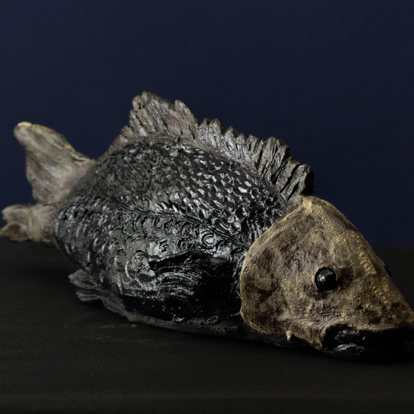 Keramik-Skulptur „Stiller Grund“ von Jutta Eger, schwarzer Ton, stilisierte Fischform mit ruhiger Linienführung, Vorderansicht rechts.