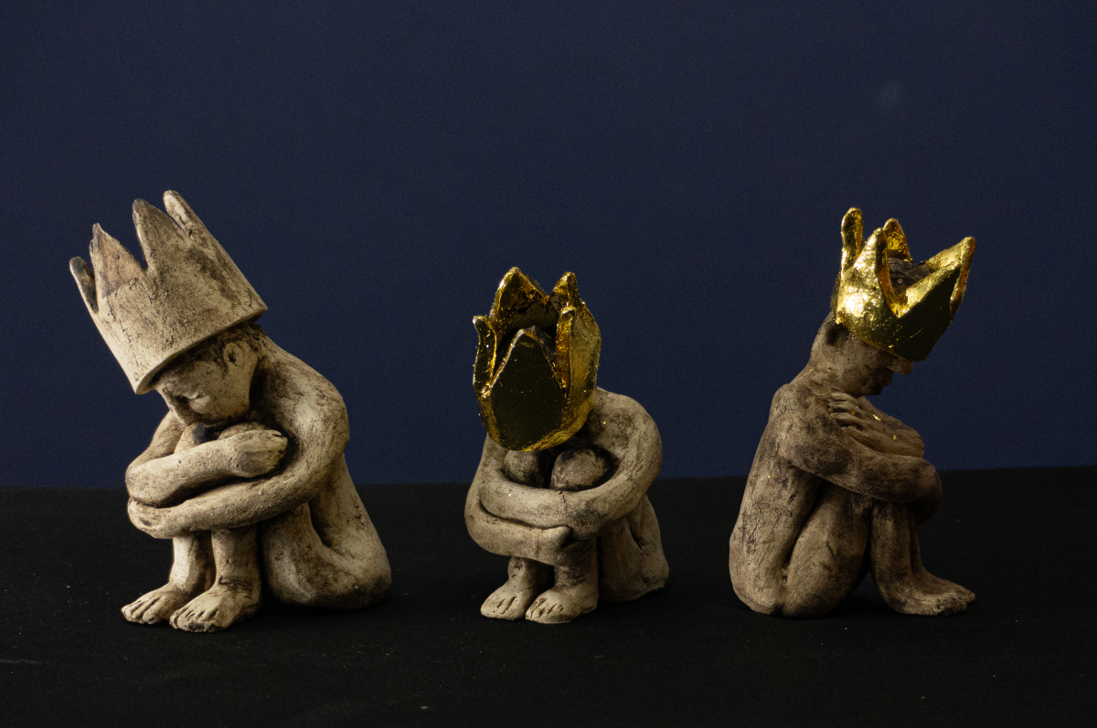Keramik-Skulpturengruppe „Die Bürde der Erwählten“ von Jutta Eger, Engobe-Oberfläche mit teilweise goldbezogenen Kronen, mehrere figurative Formen als zusammenhängendes Konzept der Bürde, Vorderansicht.
