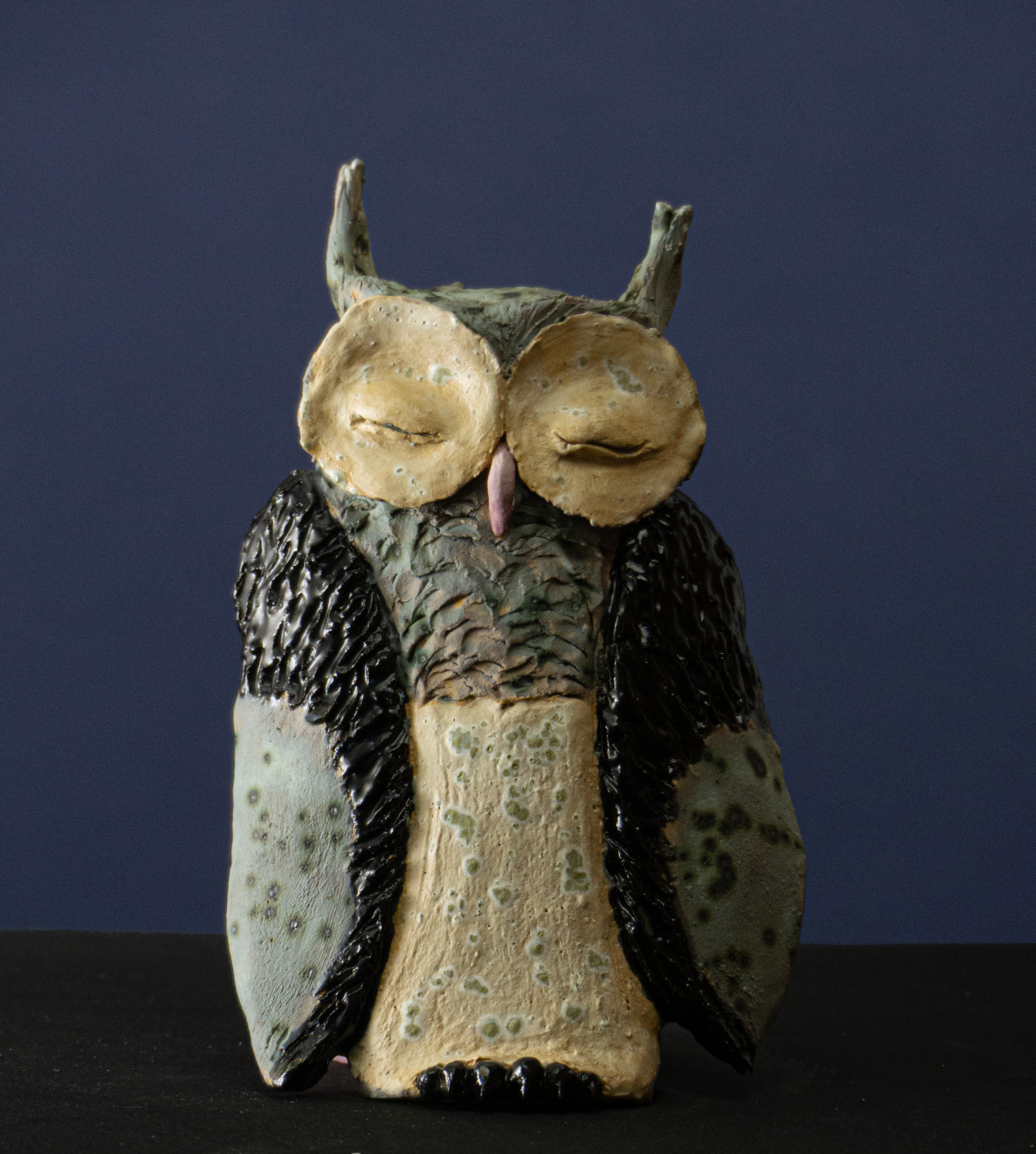 Keramik-Skulptur „Eule“ von Jutta Eger, weißer Ton mit glasierter Oberfläche, flache Wandarbeit mit reliefartiger, dennoch deutlich dreidimensionaler Ausformung, Vorderansicht.